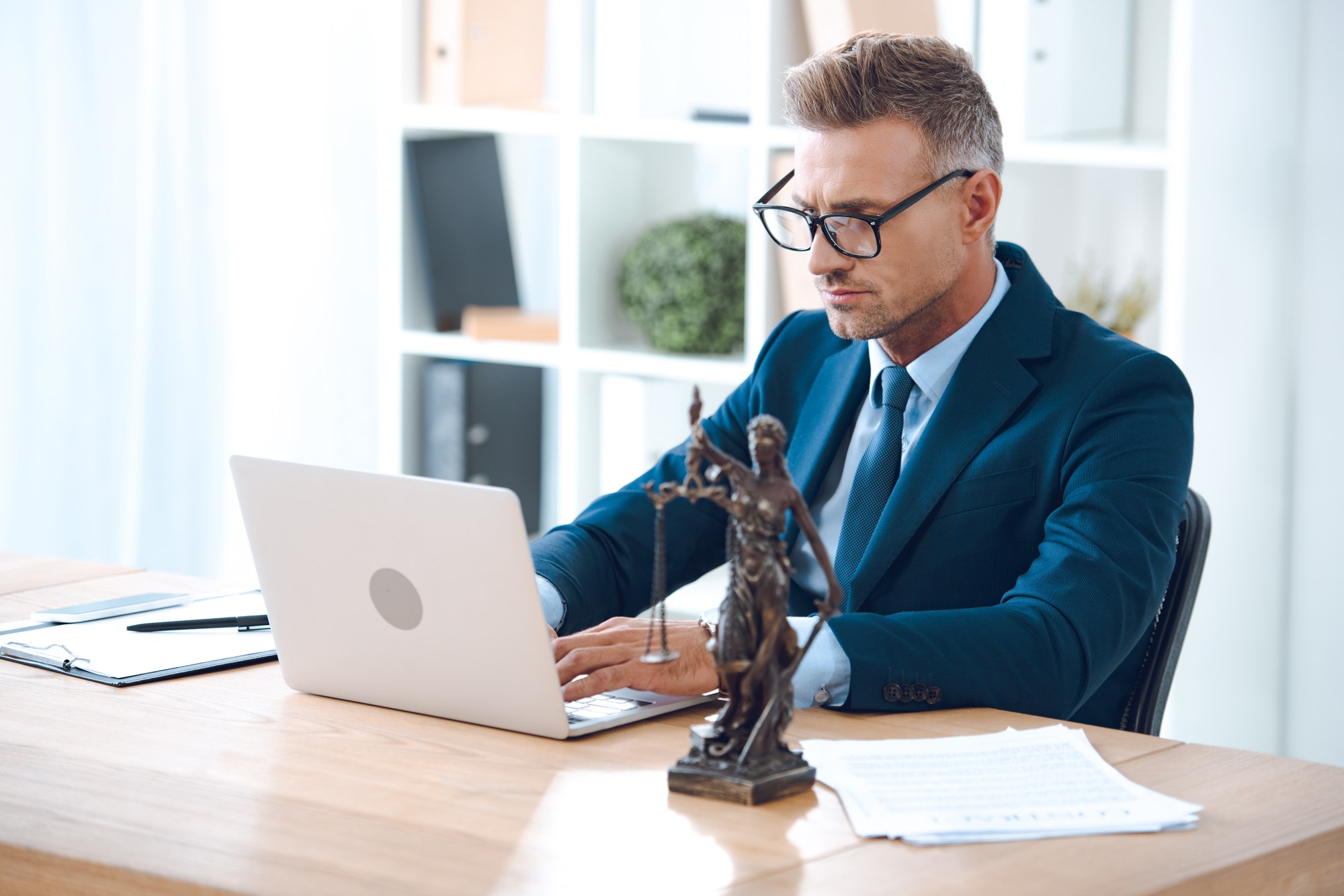 handsome-lawyer-in-eyeglasses-using-laptop-at-workplace